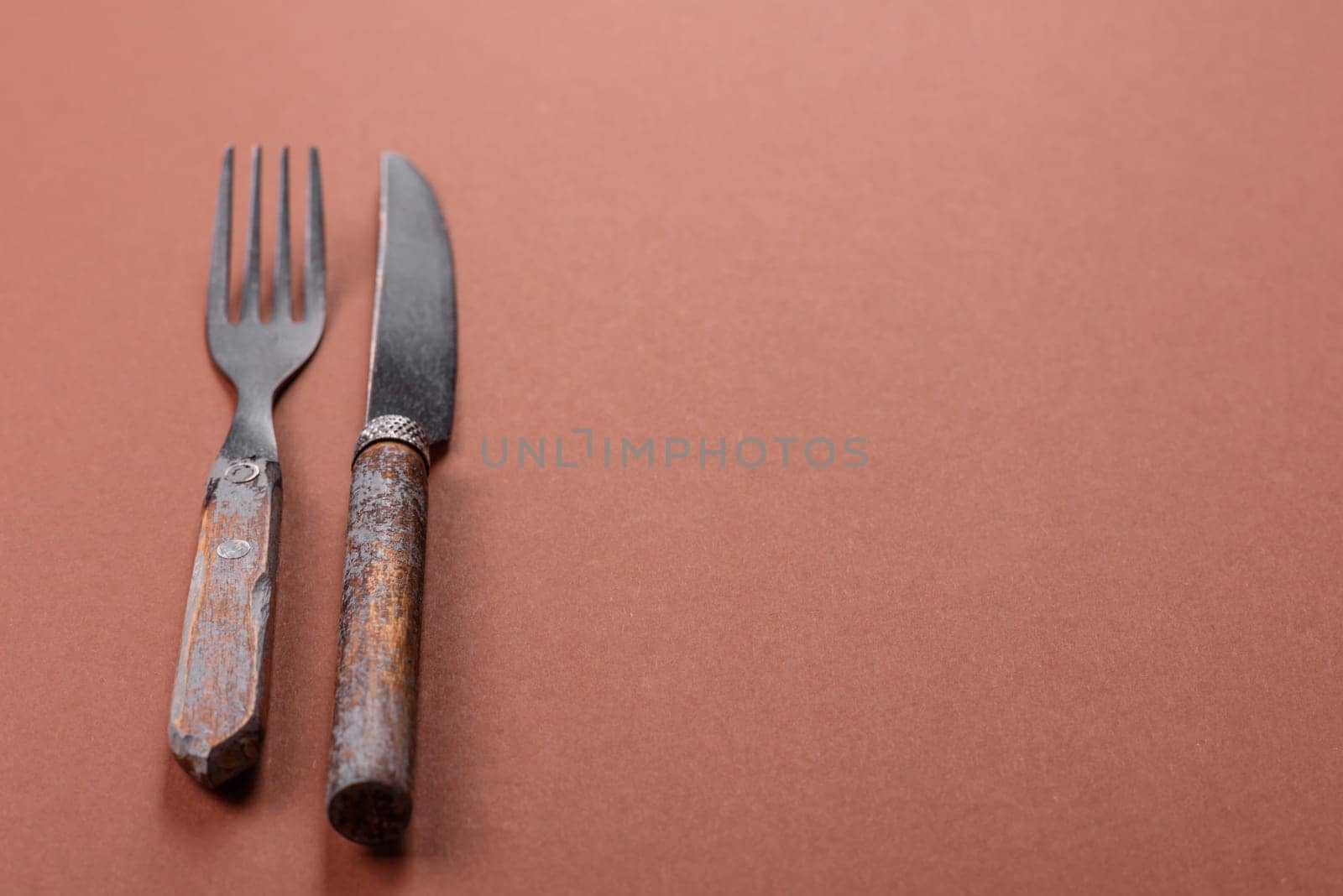 Knife and fork, cutlery on a brown dining table. Utensils and crockery for preparing dinner