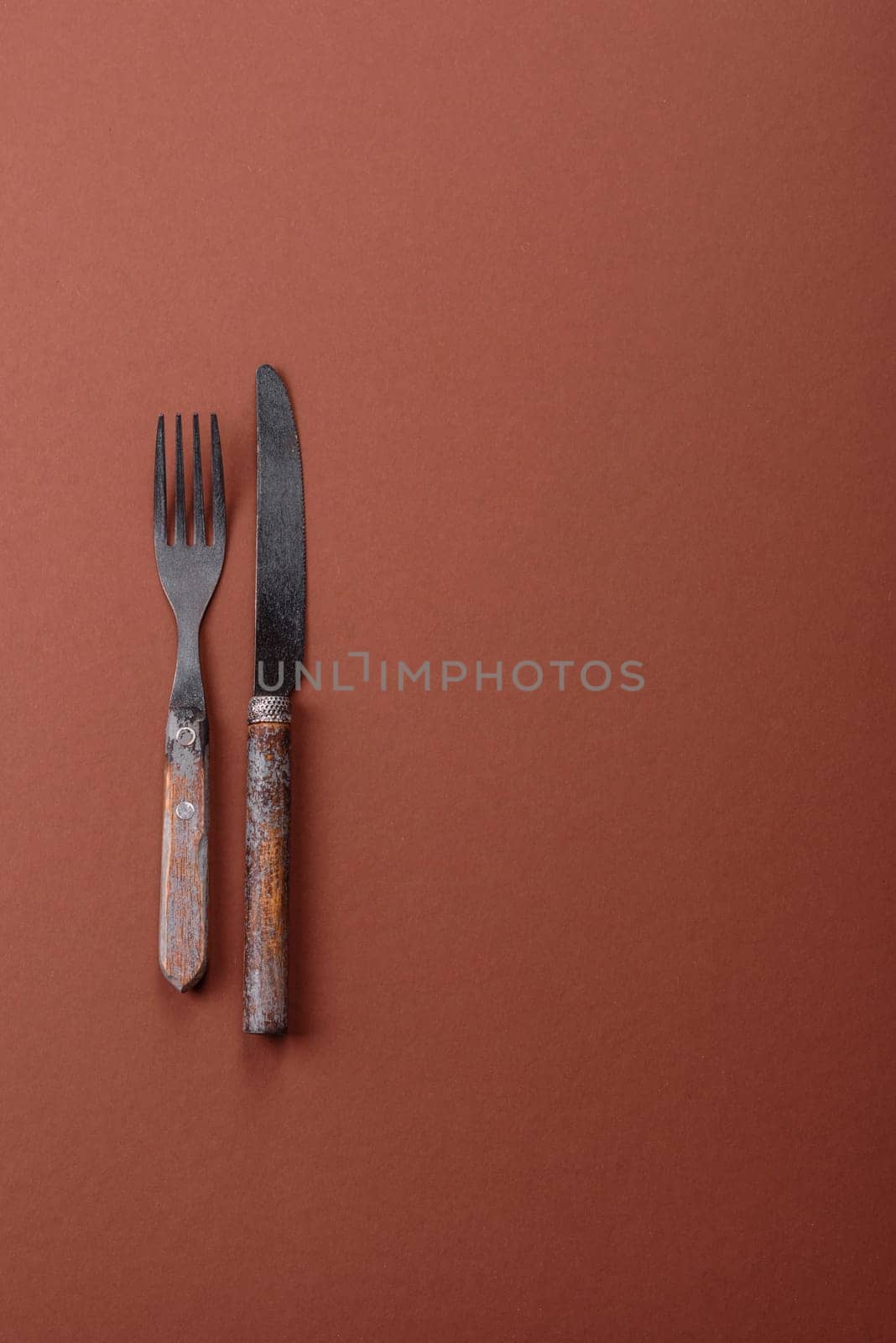 Knife and fork, cutlery on a brown dining table. Utensils and crockery for preparing dinner