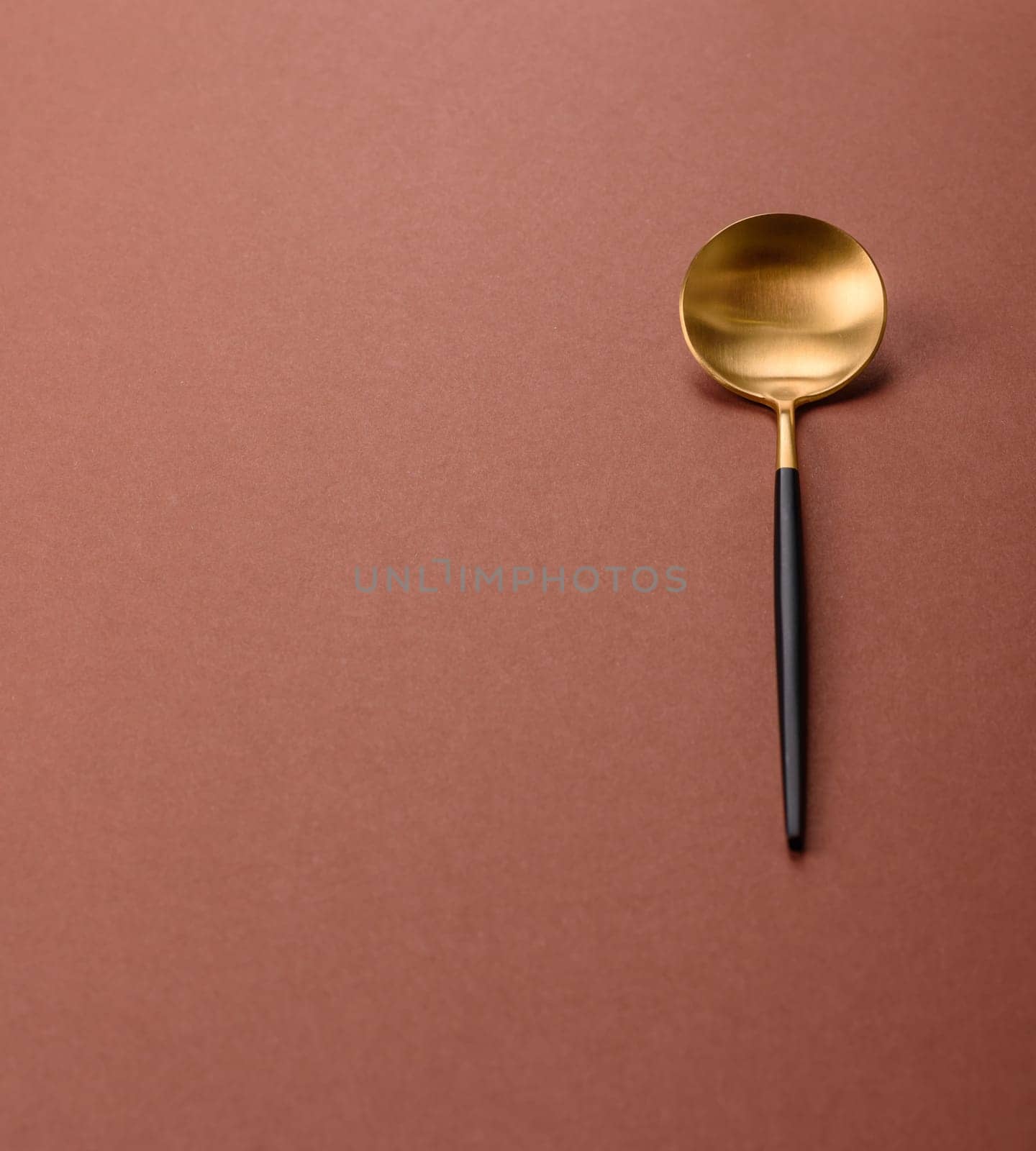 Empty metal spoon on a monochrome brown background. Cutlery on the dining table