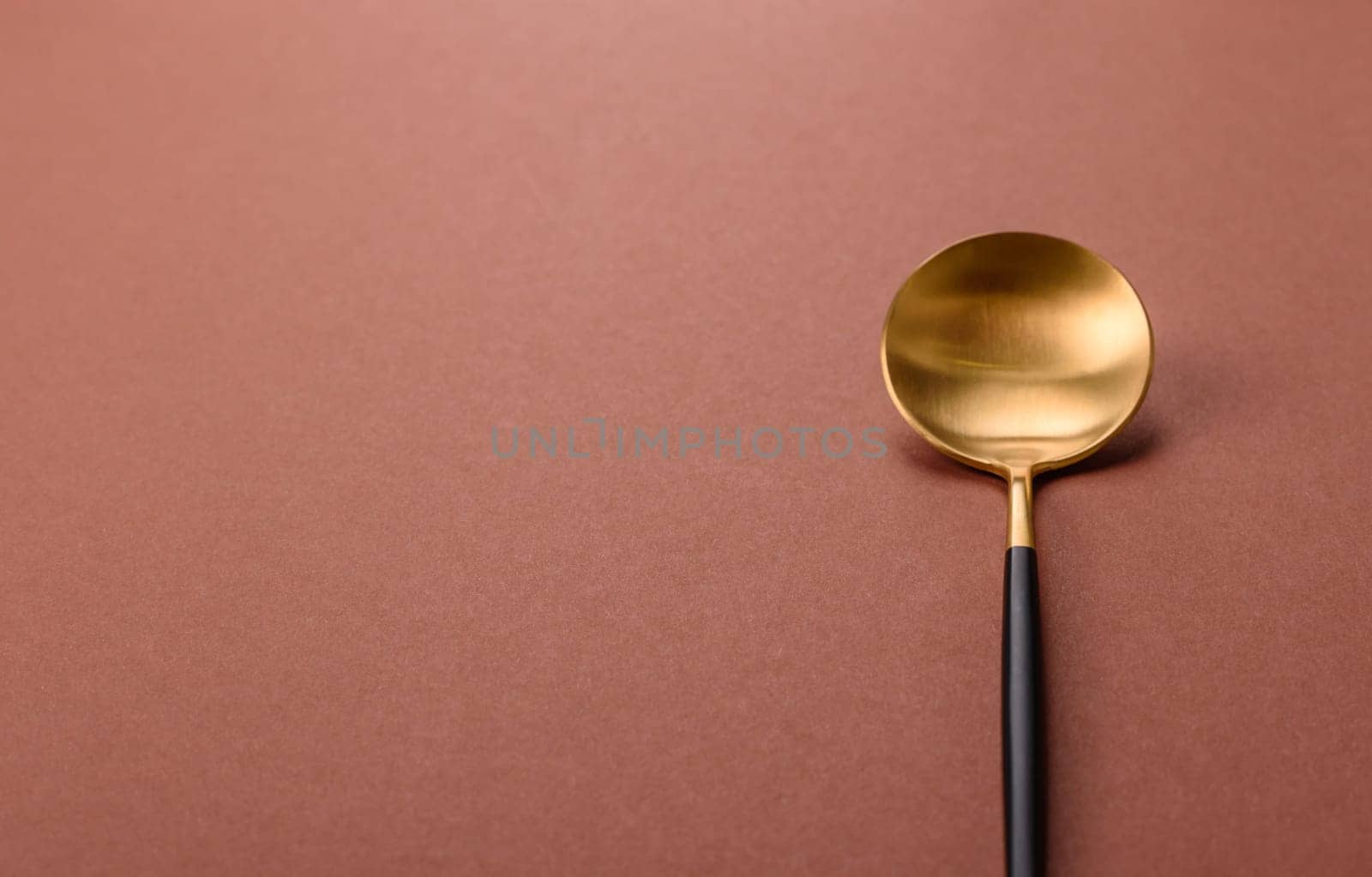 Empty metal spoon on a monochrome brown background. Cutlery on the dining table