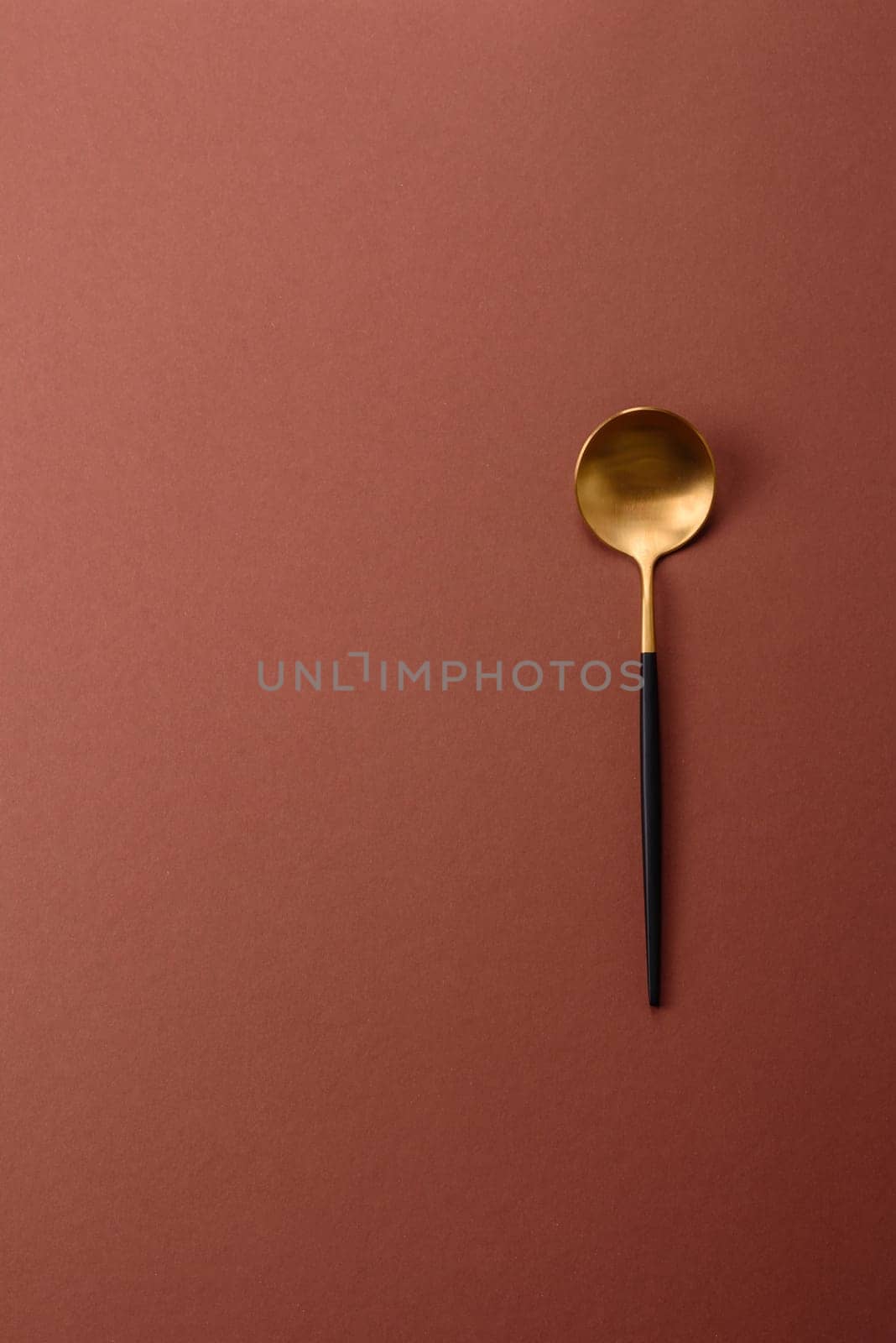 Empty metal spoon on a monochrome brown background. Cutlery on the dining table