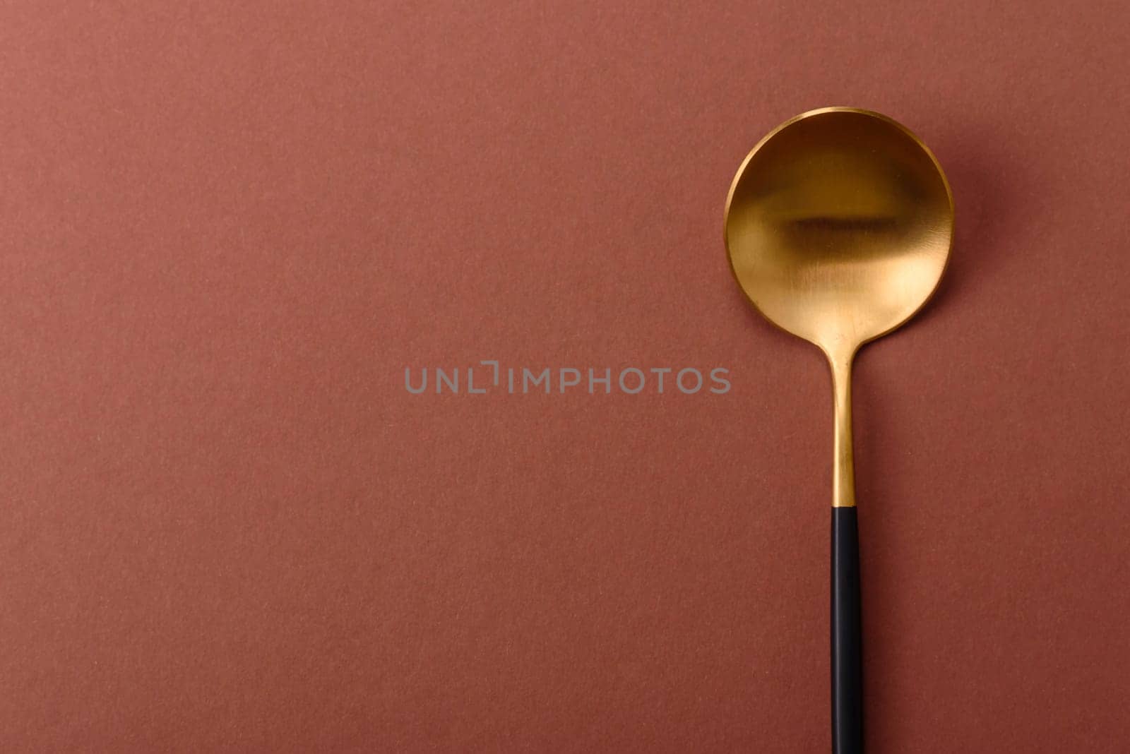 Empty metal spoon on a monochrome brown background. Cutlery on the dining table