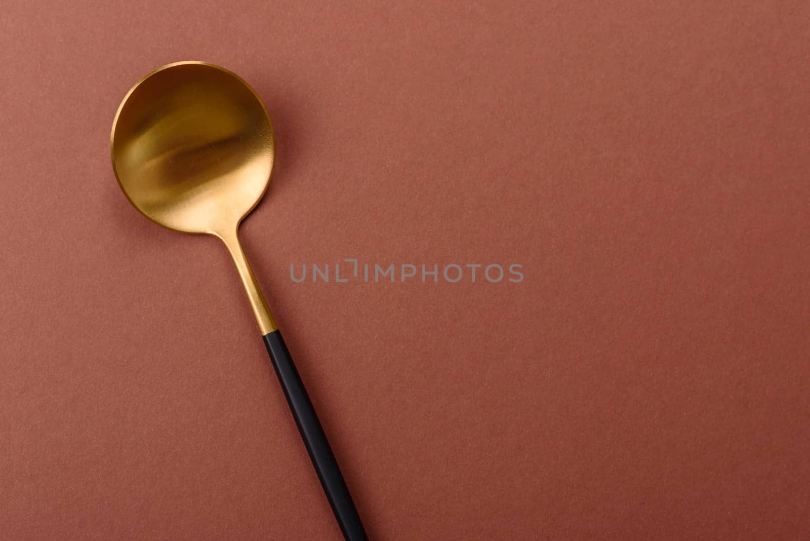 Empty metal spoon on a monochrome brown background. Cutlery on the dining table