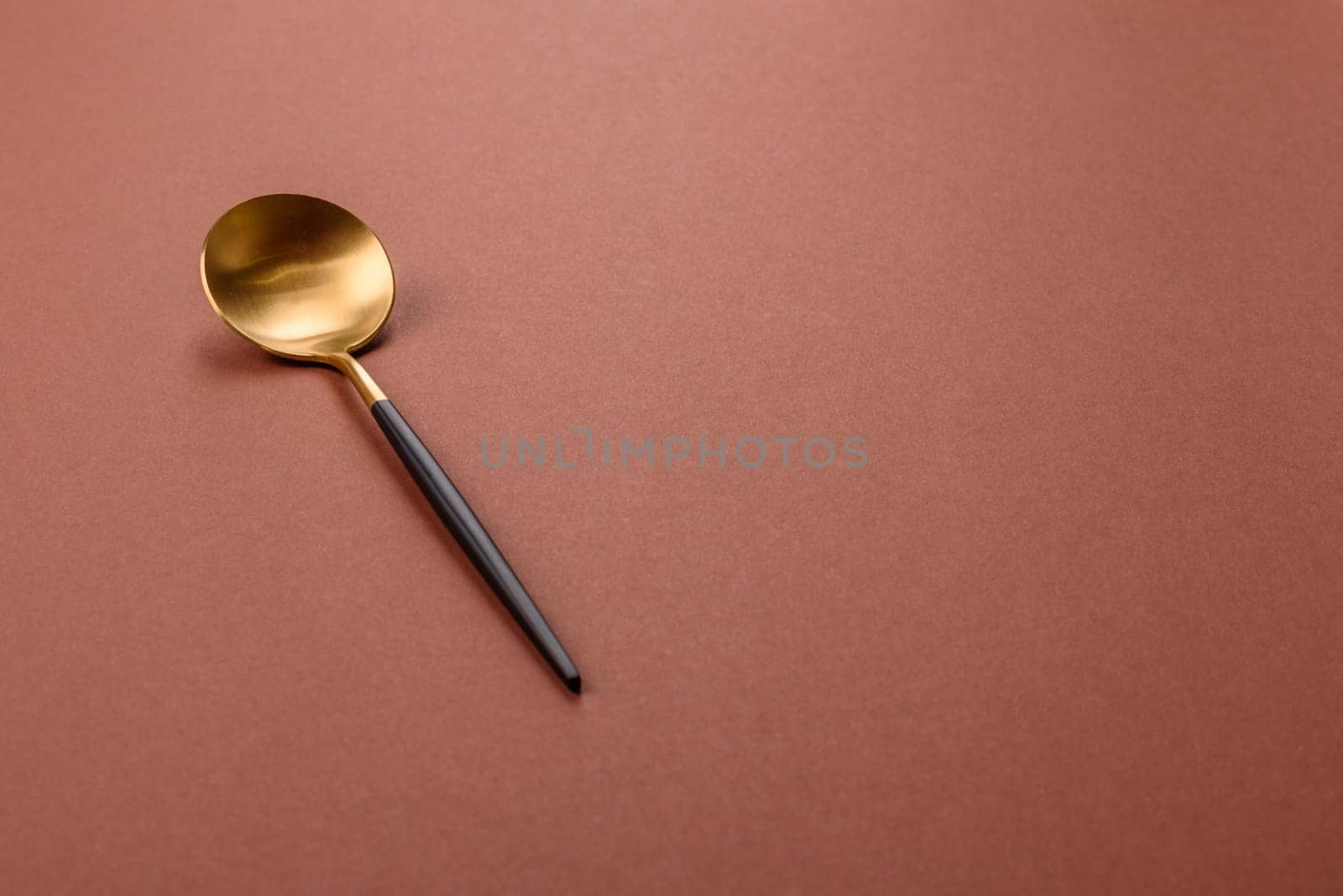 Empty metal spoon on a monochrome brown background. Cutlery on the dining table