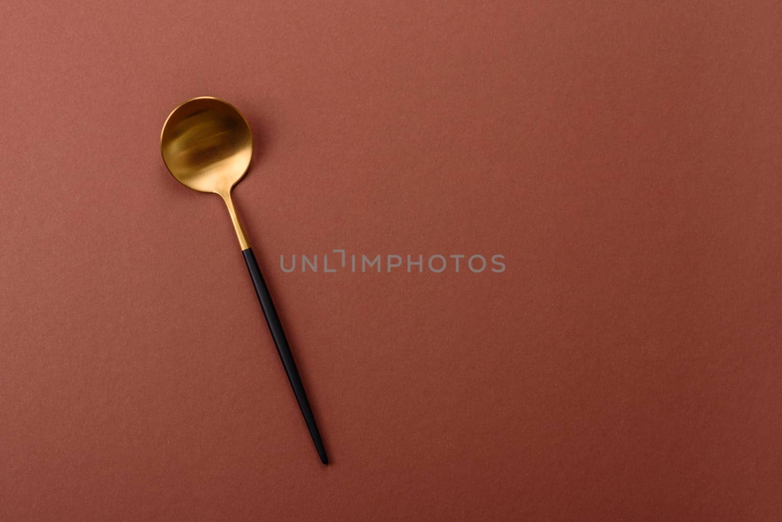 Empty metal spoon on a monochrome brown background. Cutlery on the dining table