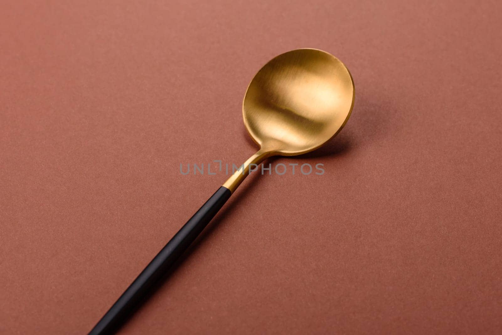 Empty metal spoon on a monochrome brown background. Cutlery on the dining table