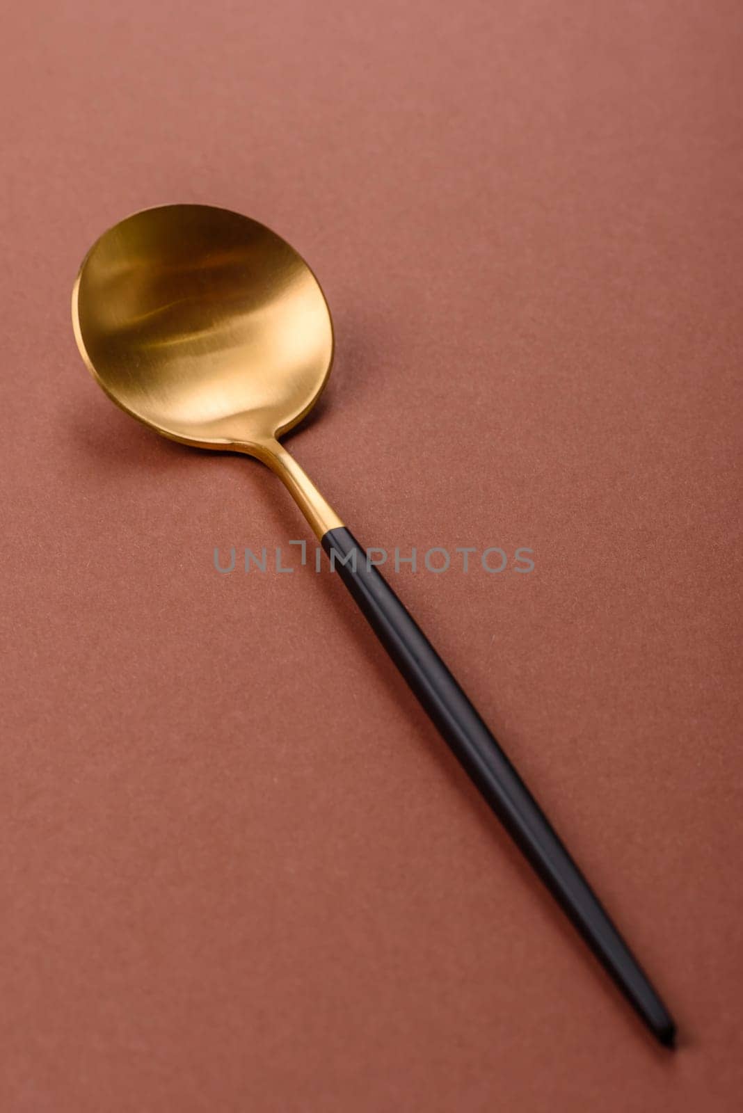 Empty metal spoon on a monochrome brown background. Cutlery on the dining table