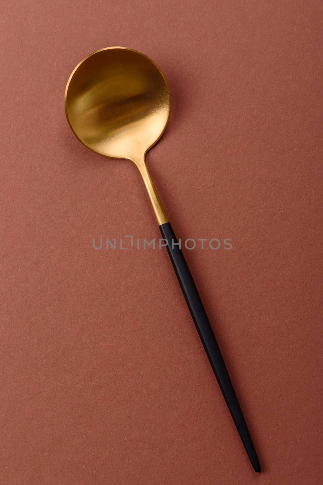 Empty metal spoon on a monochrome brown background. Cutlery on the dining table
