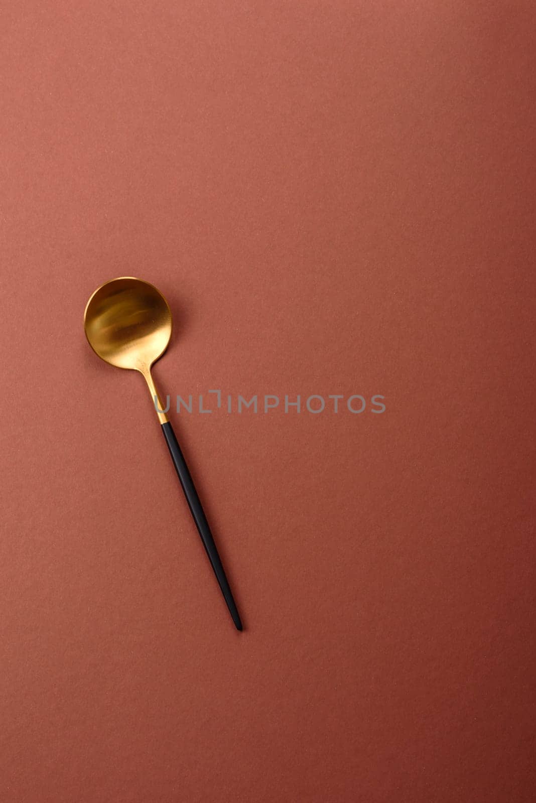 Empty metal spoon on a monochrome brown background. Cutlery on the dining table