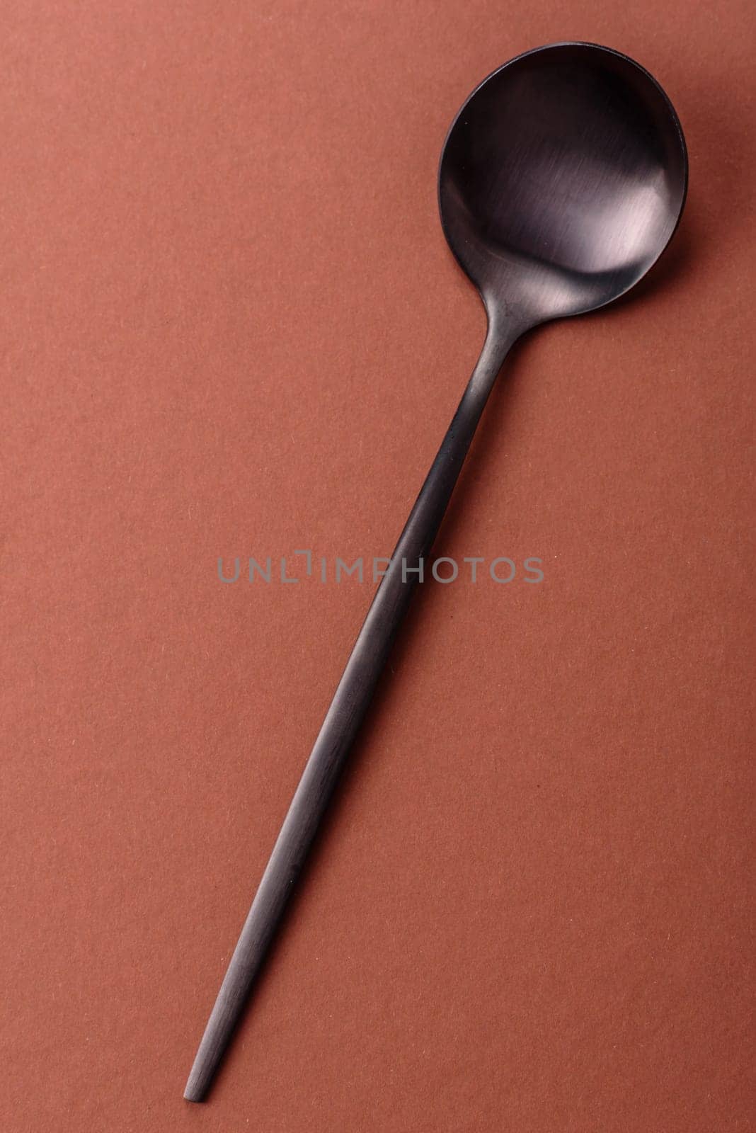 Empty metal spoon on a monochrome brown background. Cutlery on the dining table
