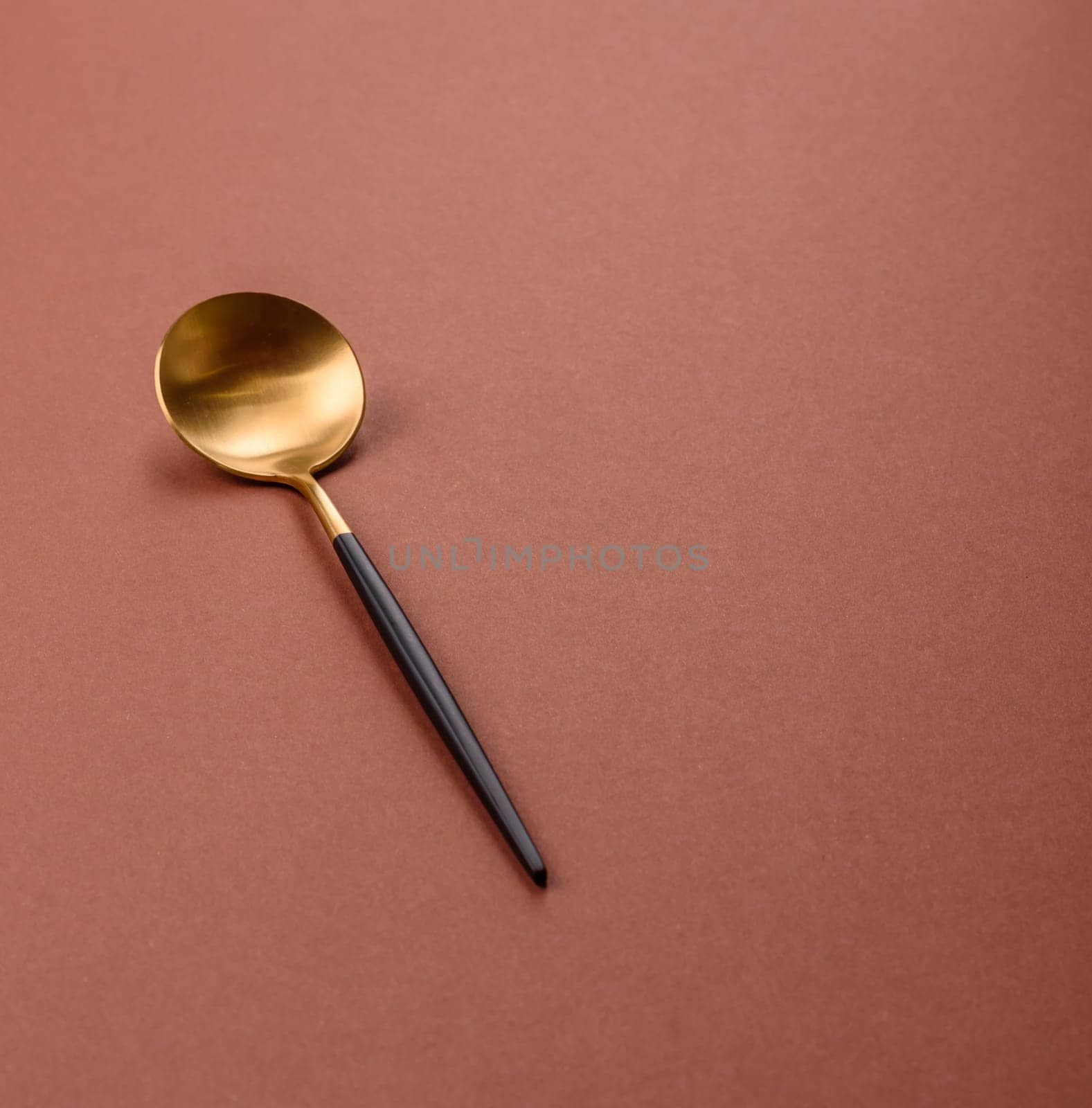 Empty metal spoon on a monochrome brown background. Cutlery on the dining table