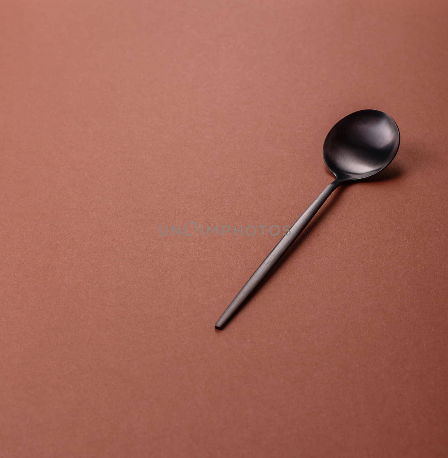 Empty metal spoon on a monochrome brown background. Cutlery on the dining table