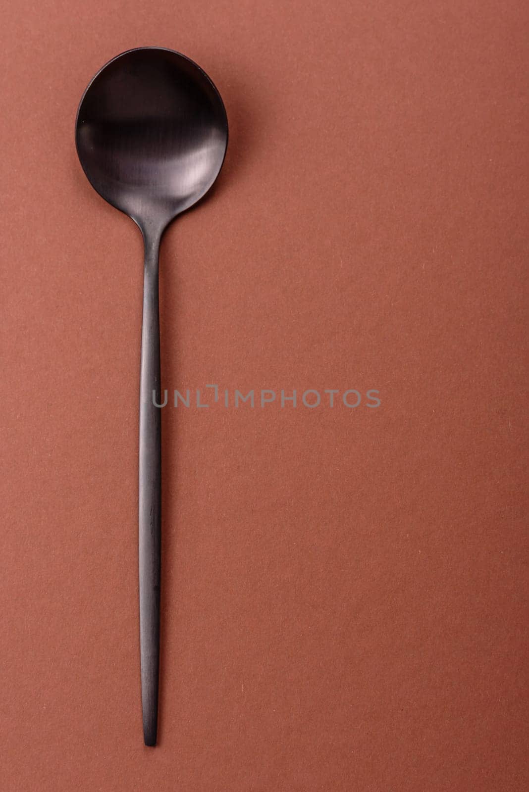 Empty metal spoon on a monochrome brown background. Cutlery on the dining table