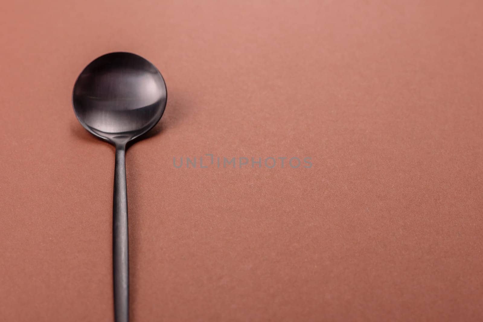 Empty metal spoon on a monochrome brown background. Cutlery on the dining table
