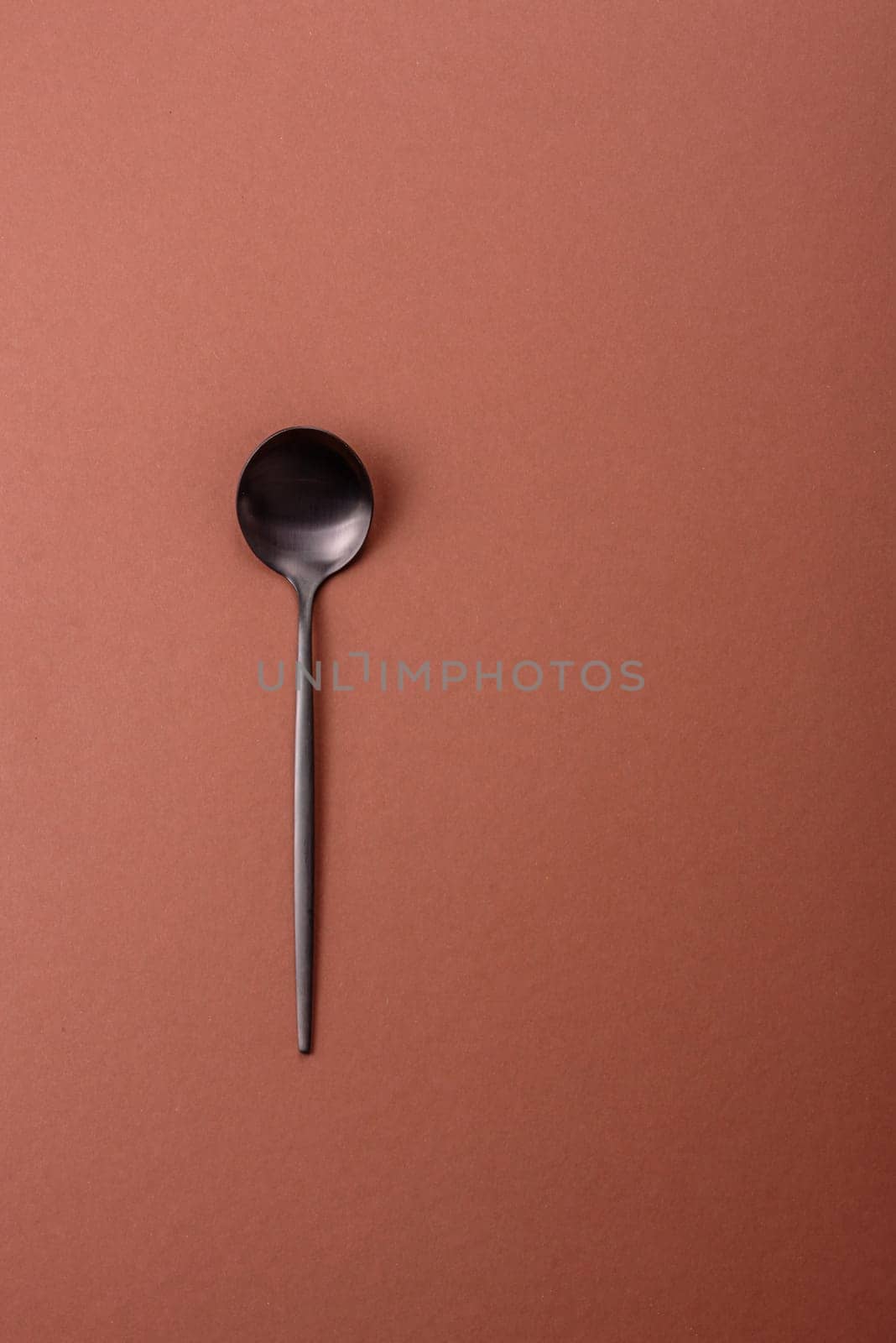Empty metal spoon on a monochrome brown background. Cutlery on the dining table