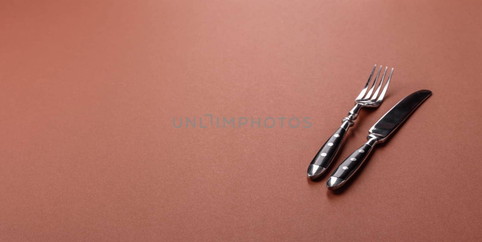Knife and fork, cutlery on a brown dining table. Utensils and crockery for preparing dinner