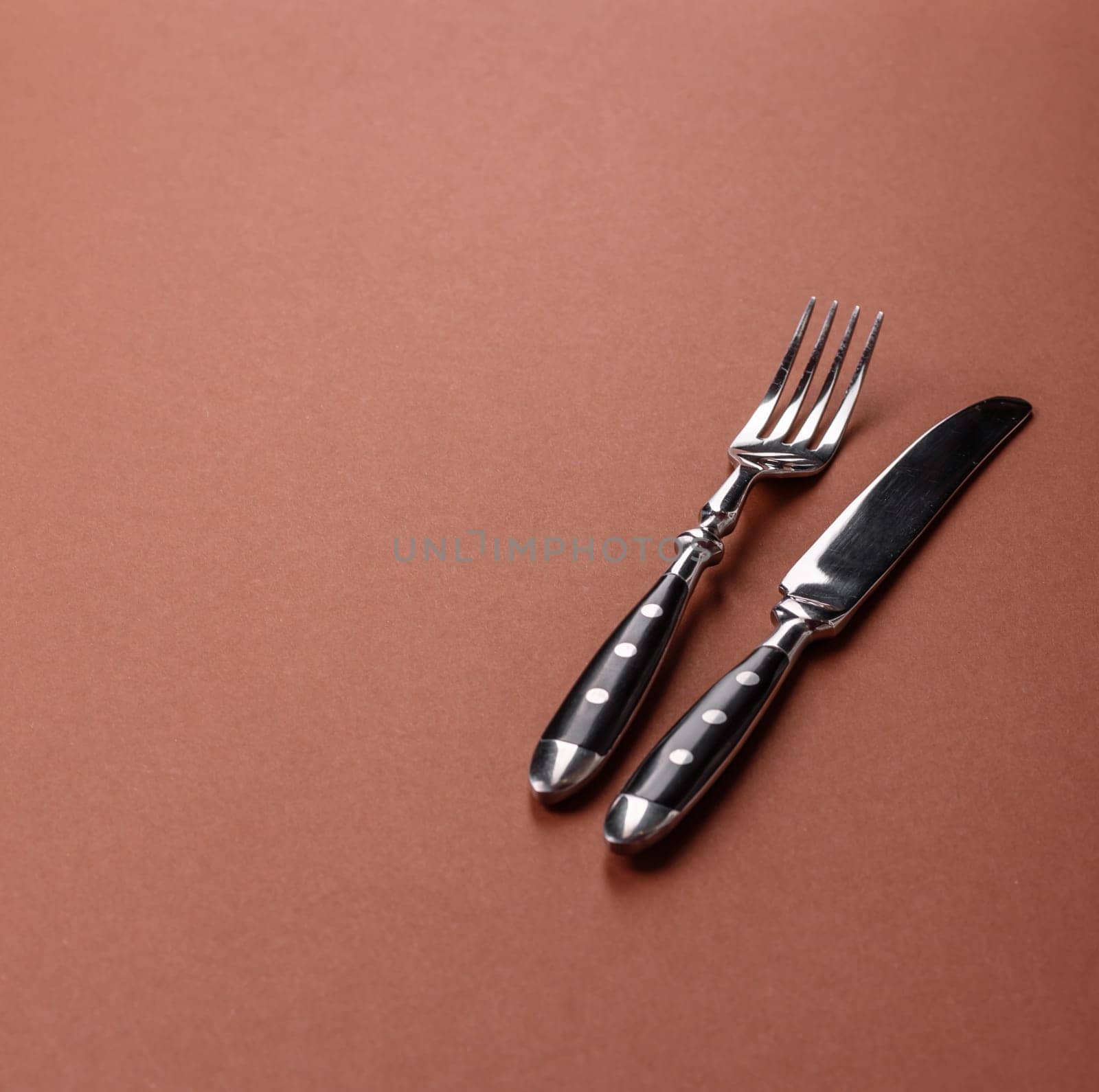 Knife and fork, cutlery on a brown dining table. Utensils and crockery for preparing dinner