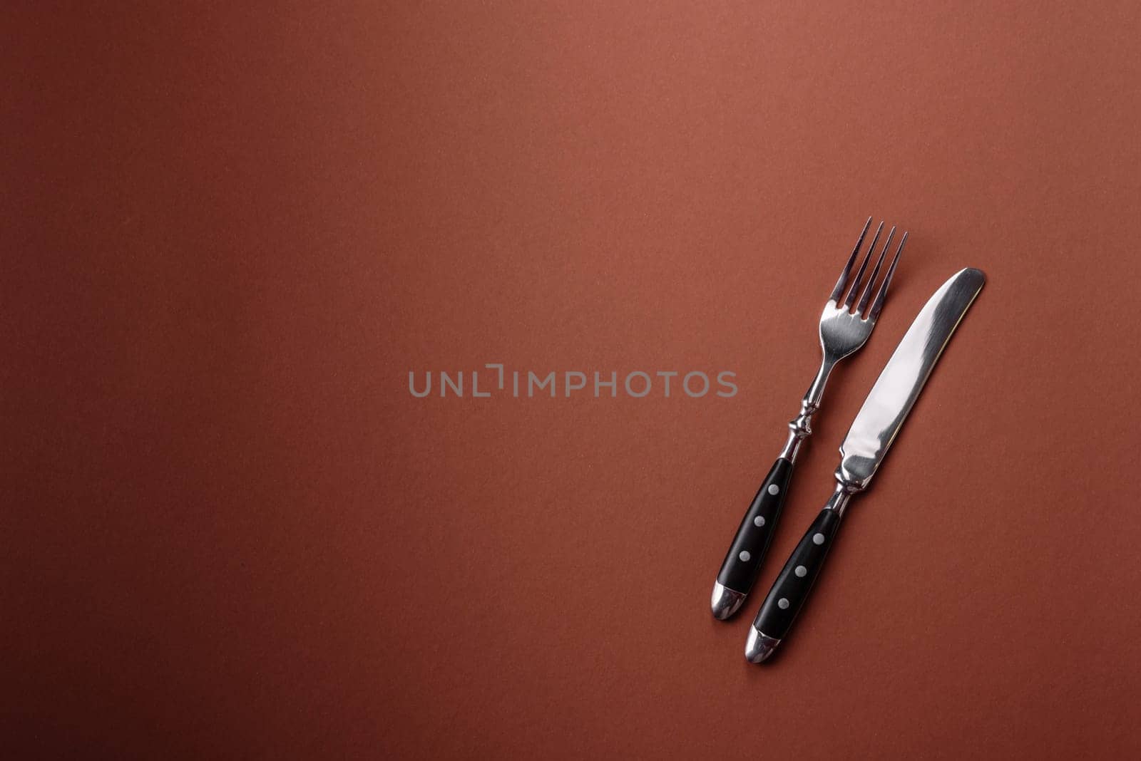 Knife and fork, cutlery on a brown dining table. Utensils and crockery for preparing dinner