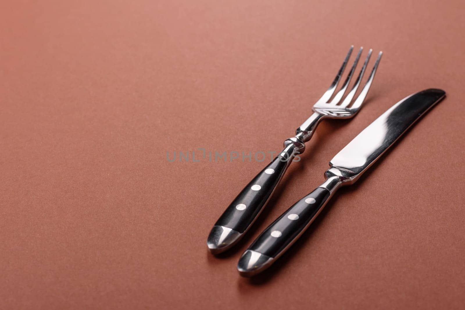 Knife and fork, cutlery on a brown dining table. Utensils and crockery for preparing dinner