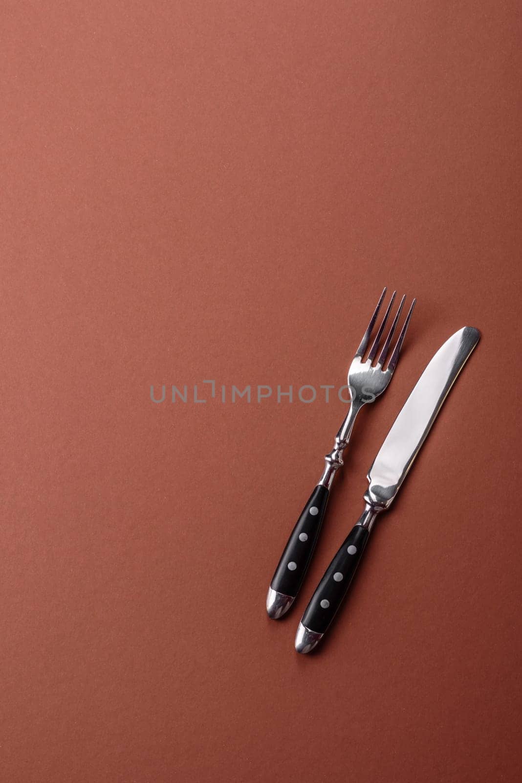 Knife and fork, cutlery on a brown dining table. Utensils and crockery for preparing dinner