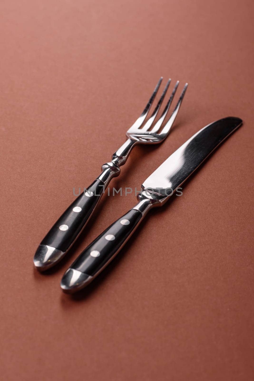 Knife and fork, cutlery on a brown dining table. Utensils and crockery for preparing dinner