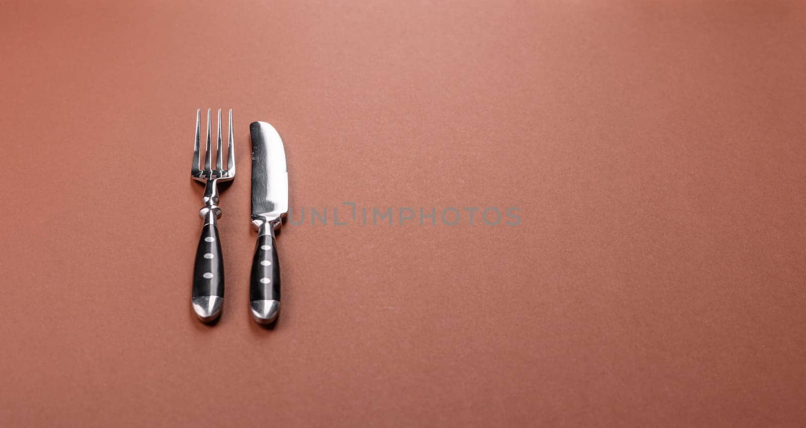 Knife and fork, cutlery on a brown dining table. Utensils and crockery for preparing dinner