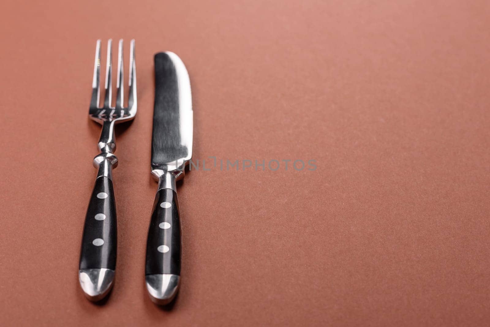 Knife and fork, cutlery on a brown dining table. Utensils and crockery for preparing dinner