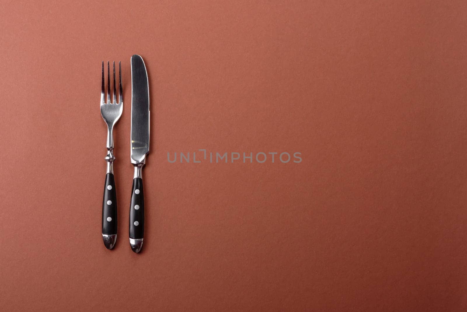 Knife and fork, cutlery on a brown dining table. Utensils and crockery for preparing dinner