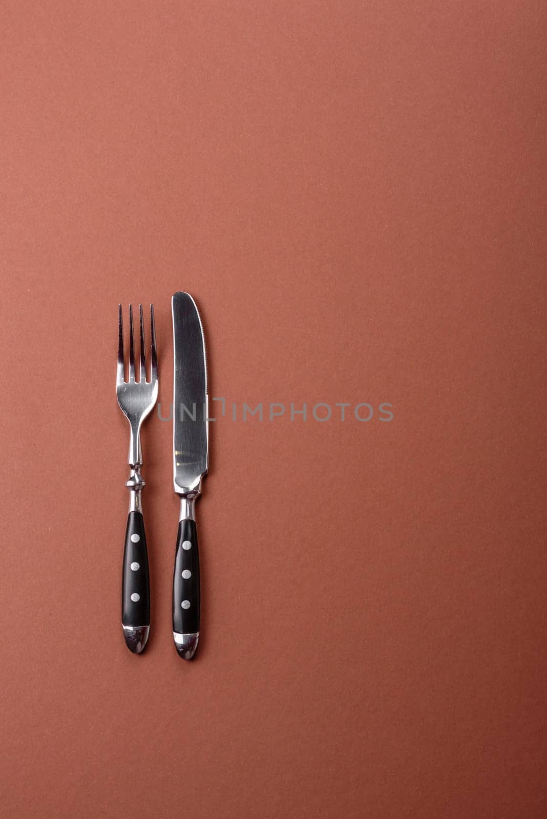 Knife and fork, cutlery on a brown dining table. Utensils and crockery for preparing dinner