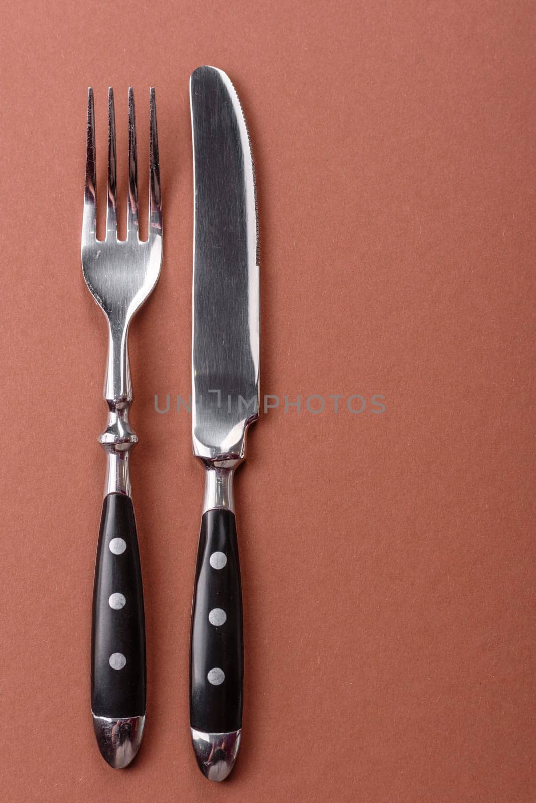 Knife and fork, cutlery on a brown dining table. Utensils and crockery for preparing dinner
