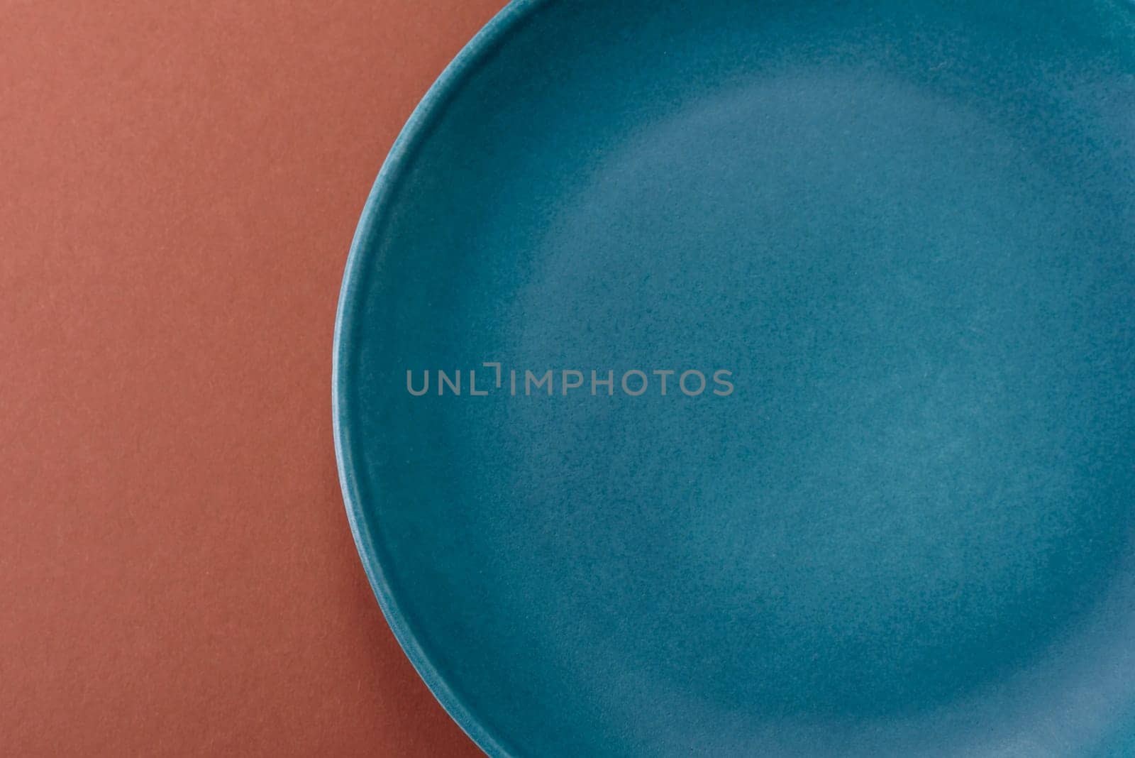 Empty ceramic plate on a monochrome brown background. Empty plate with cutlery on a dining table