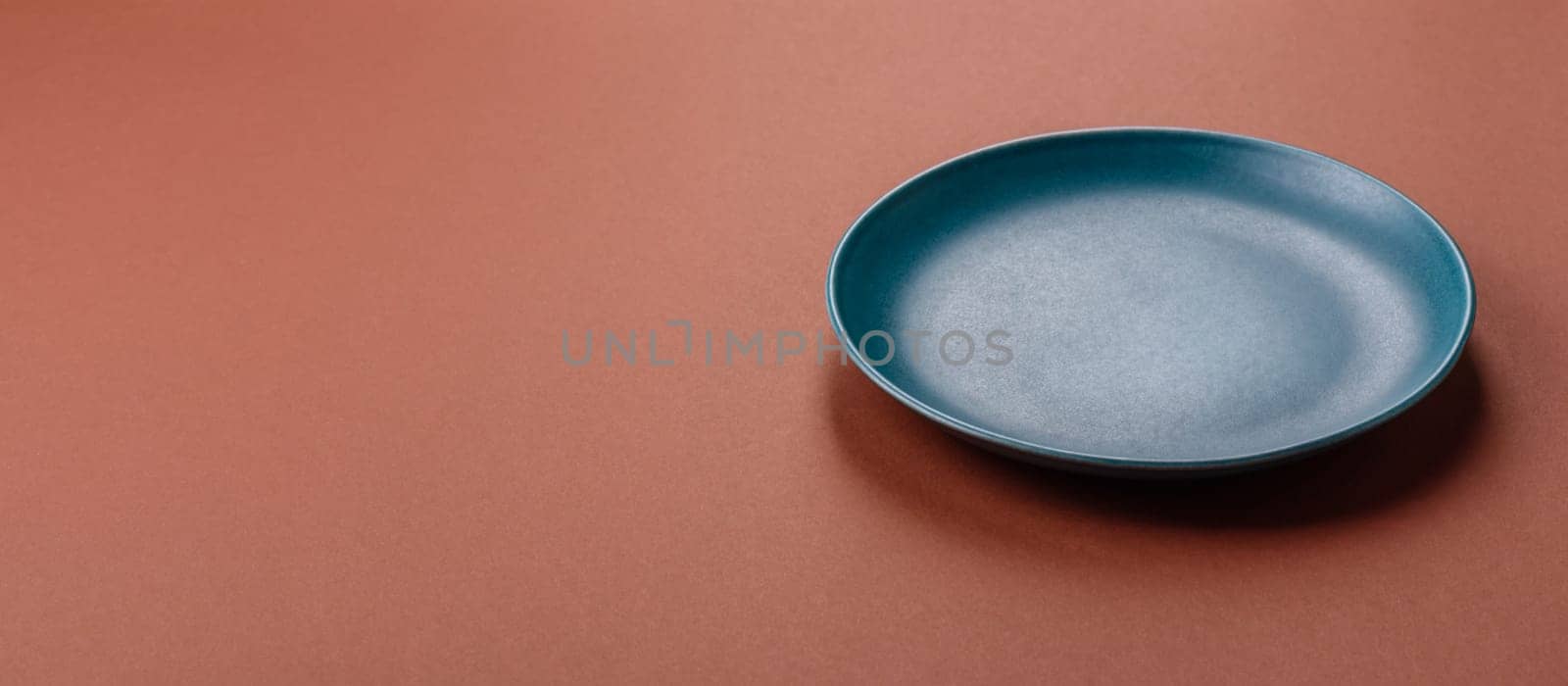 Empty ceramic plate on a monochrome brown background. Empty plate with cutlery on a dining table