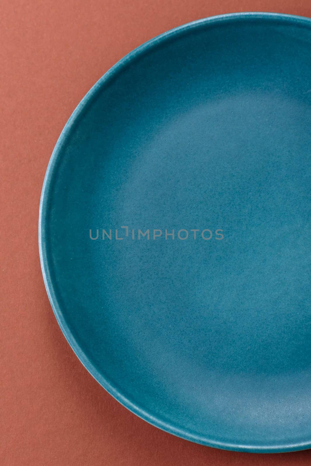 Empty ceramic plate on a monochrome brown background. Empty plate with cutlery on a dining table