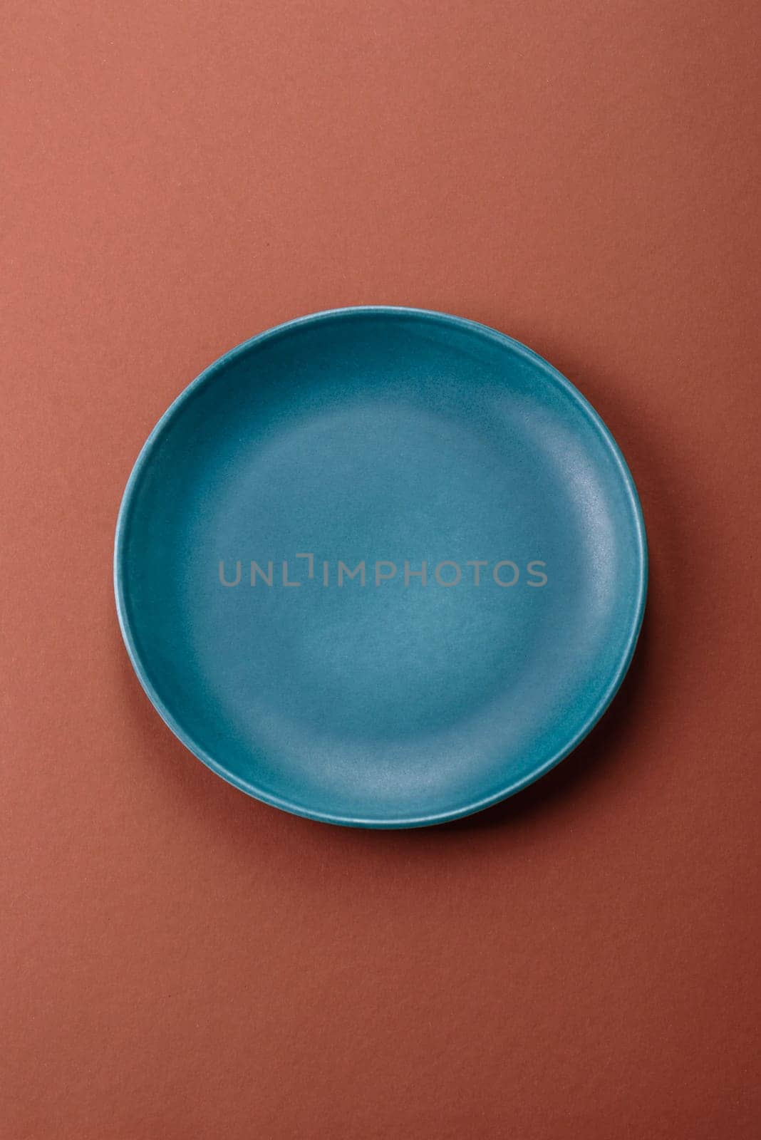 Empty ceramic plate on a monochrome brown background. Empty plate with cutlery on a dining table