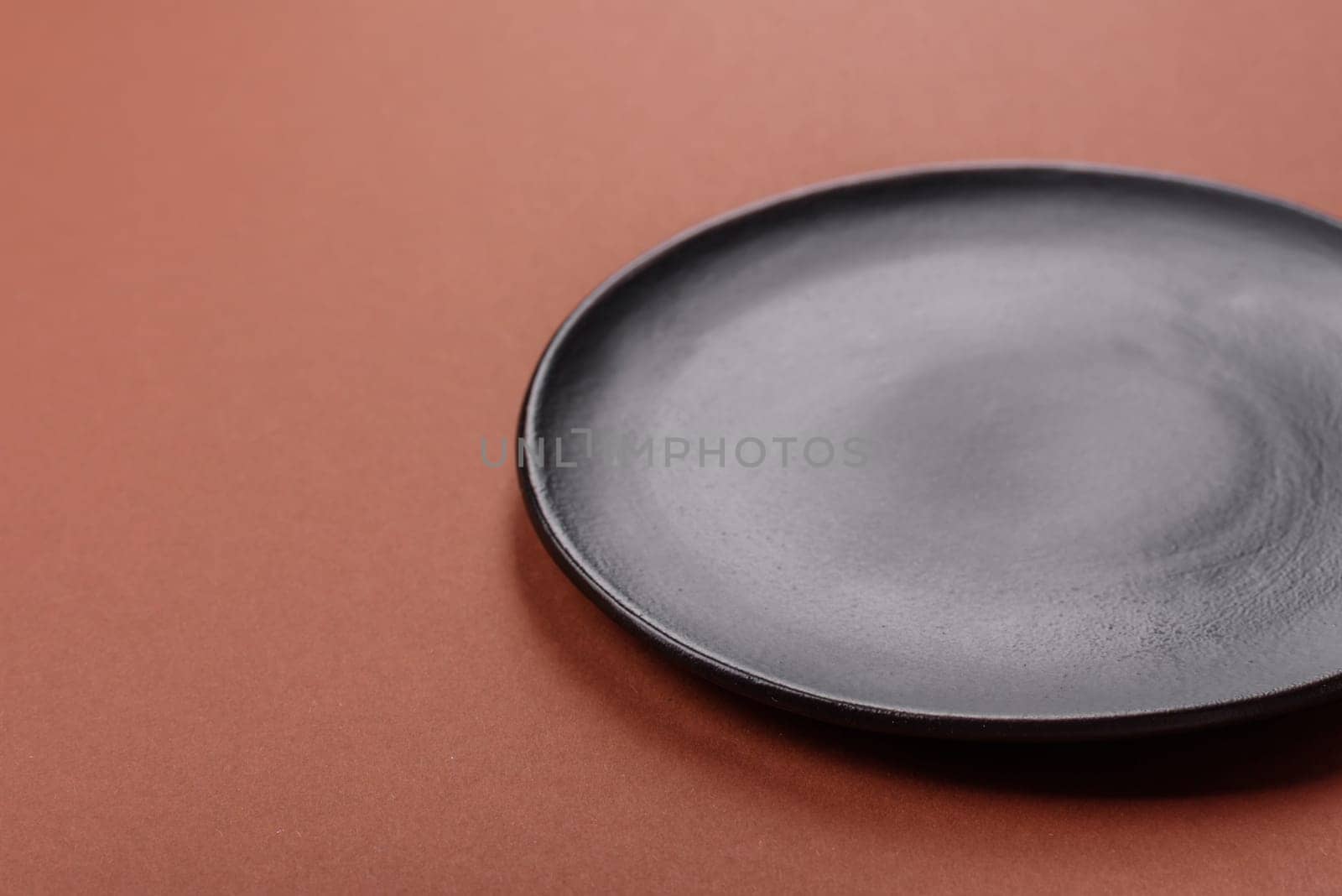 Empty ceramic plate on a monochrome brown background. Empty plate with cutlery on a dining table