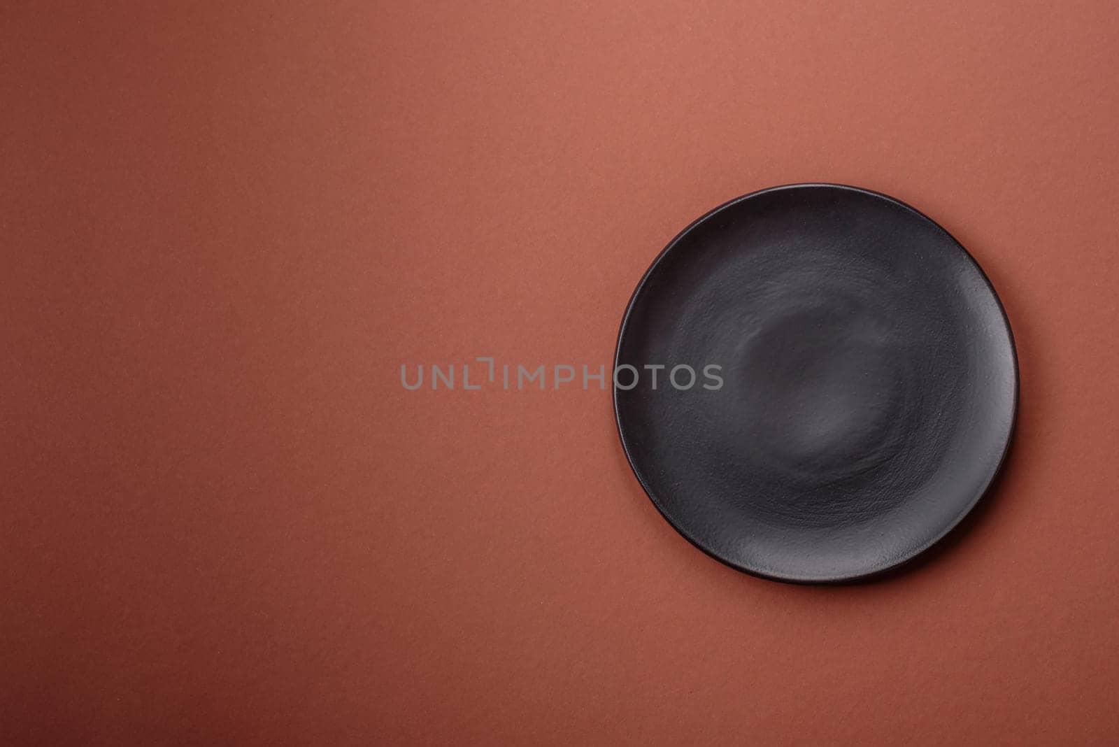 Empty ceramic plate on a monochrome brown background. Empty plate with cutlery on a dining table