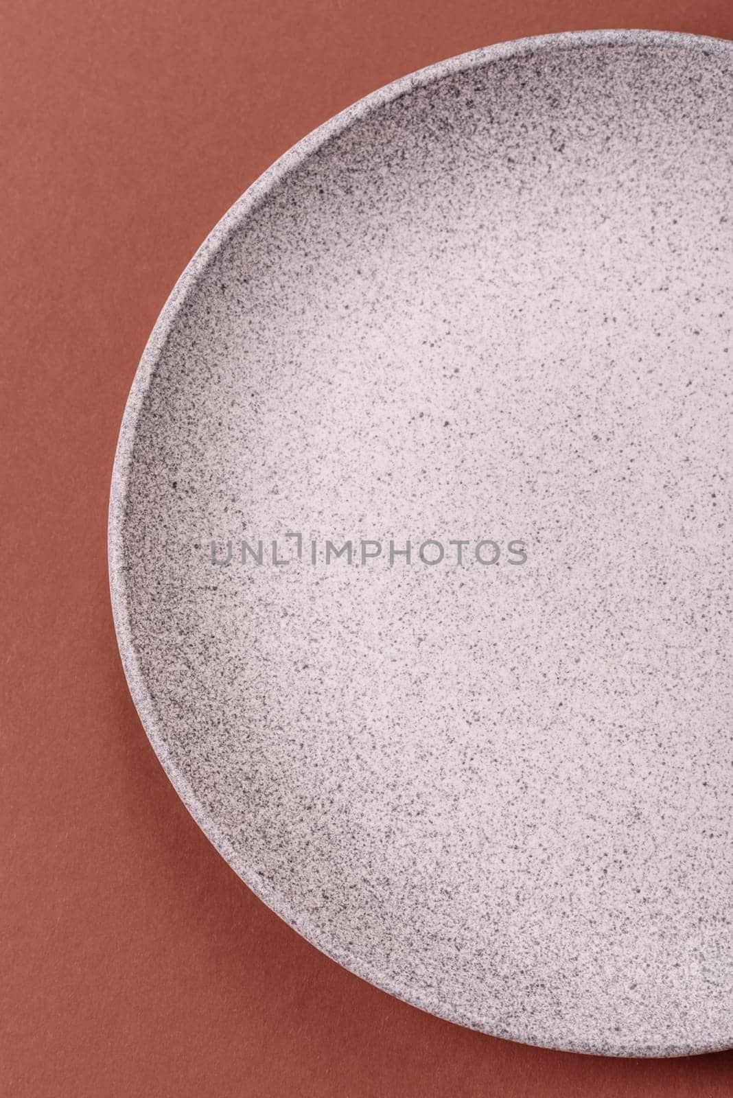 Empty ceramic plate on a monochrome brown background. Empty plate with cutlery on a dining table