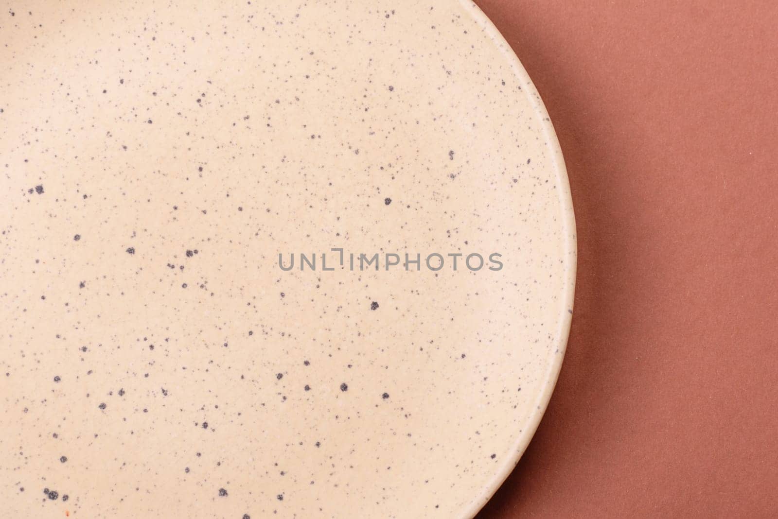 Empty ceramic plate on a monochrome brown background. Empty plate with cutlery on a dining table