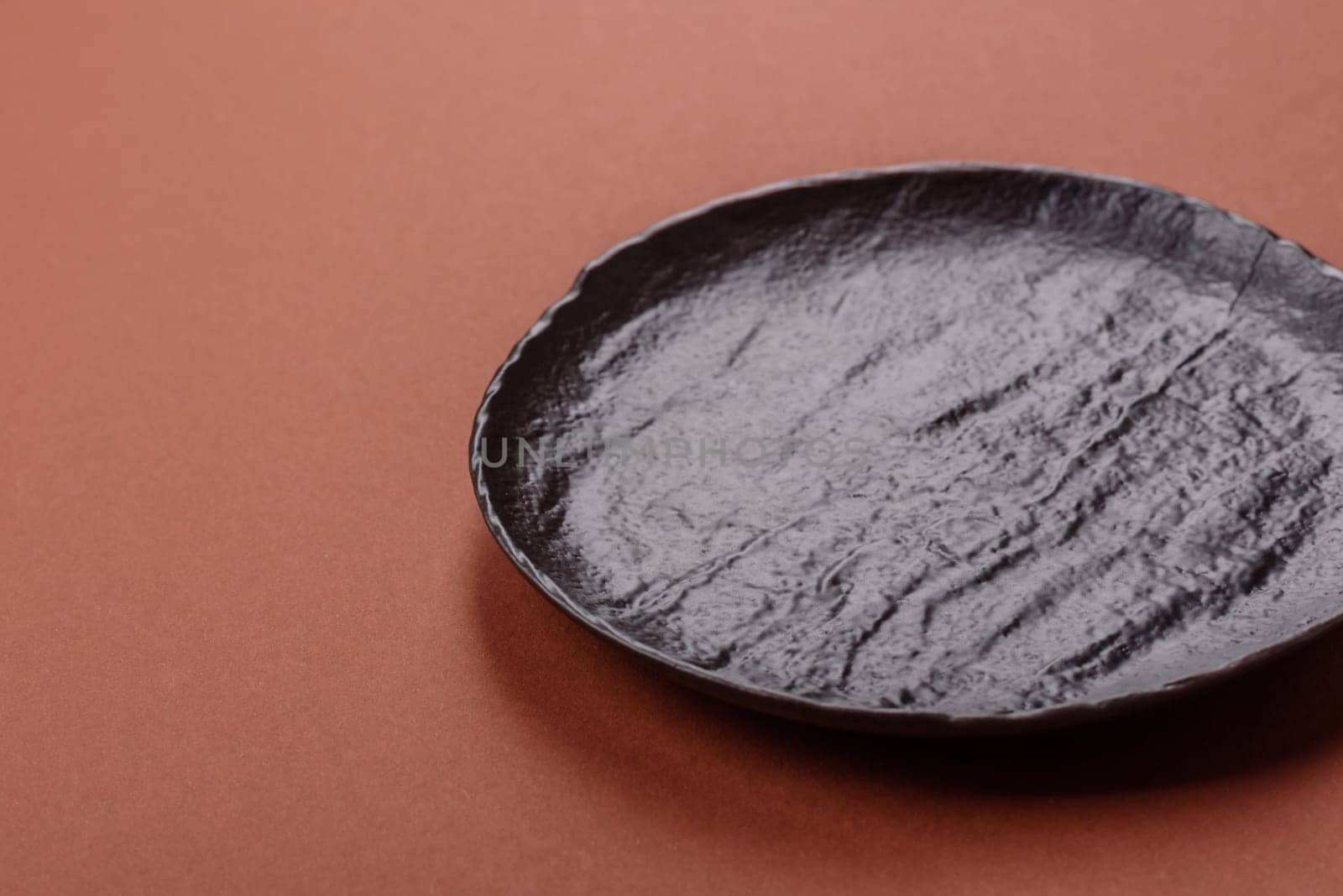 Empty ceramic plate on a monochrome brown background. Empty plate with cutlery on a dining table