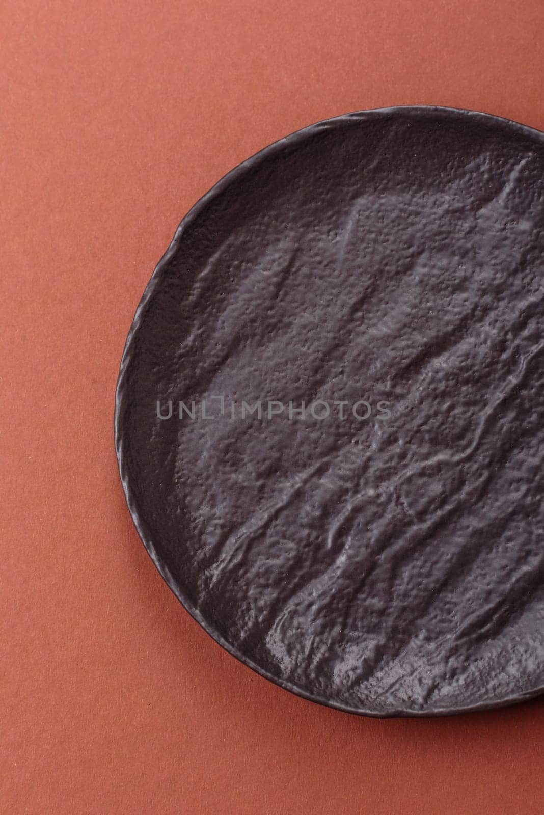 Empty ceramic plate on a monochrome brown background. Empty plate with cutlery on a dining table