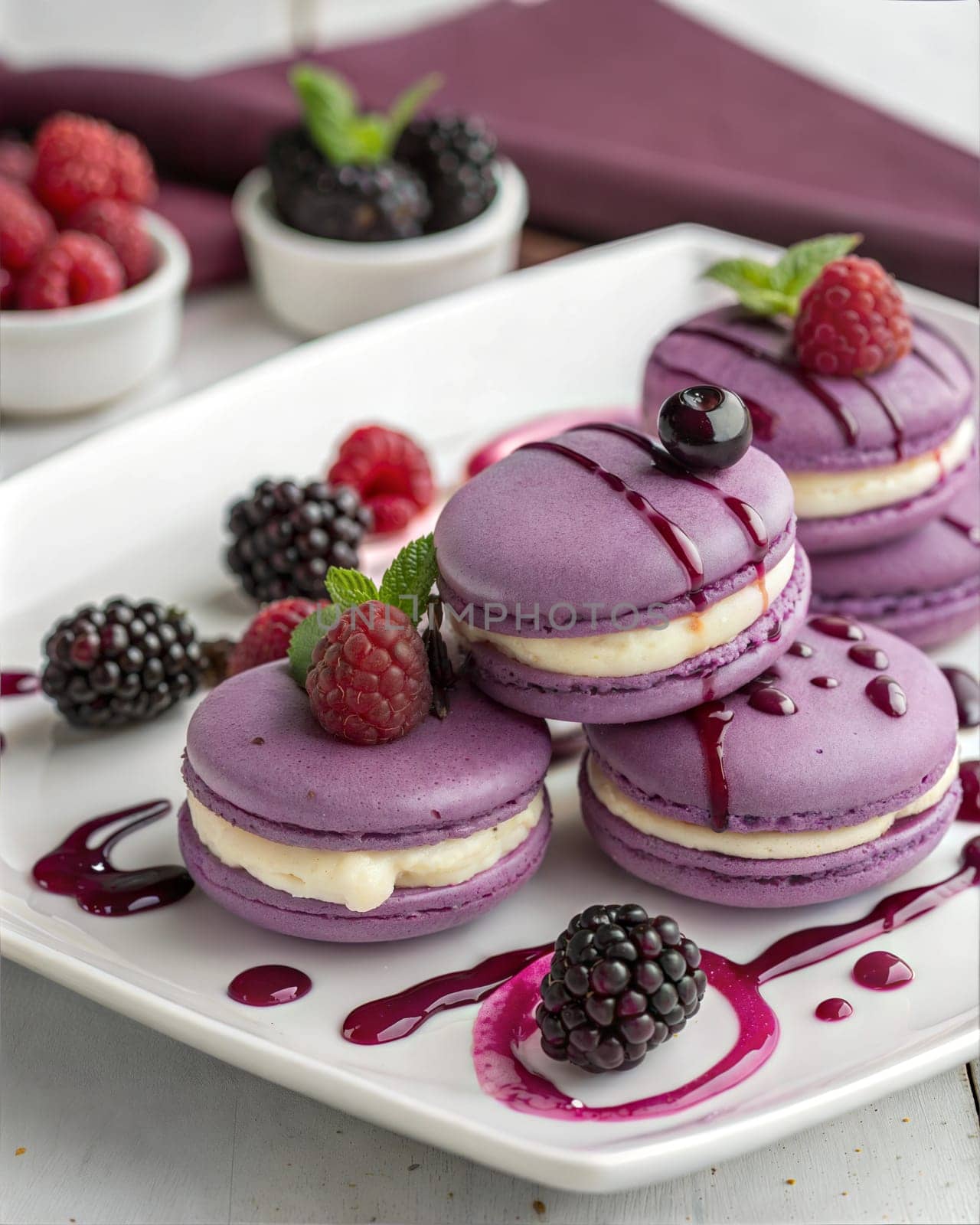 A close-up of delicious purple macarons drizzled with blackberry sauce, accompanied by fresh blackberries, perfect for dessert lovers.