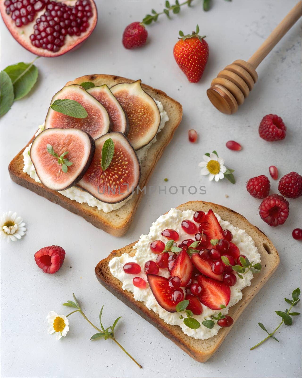 Two slices of toast topped with creamy cheese and fresh figs on one side, and strawberries, pomegranate, and honey on the other, garnished with mint and herbs.