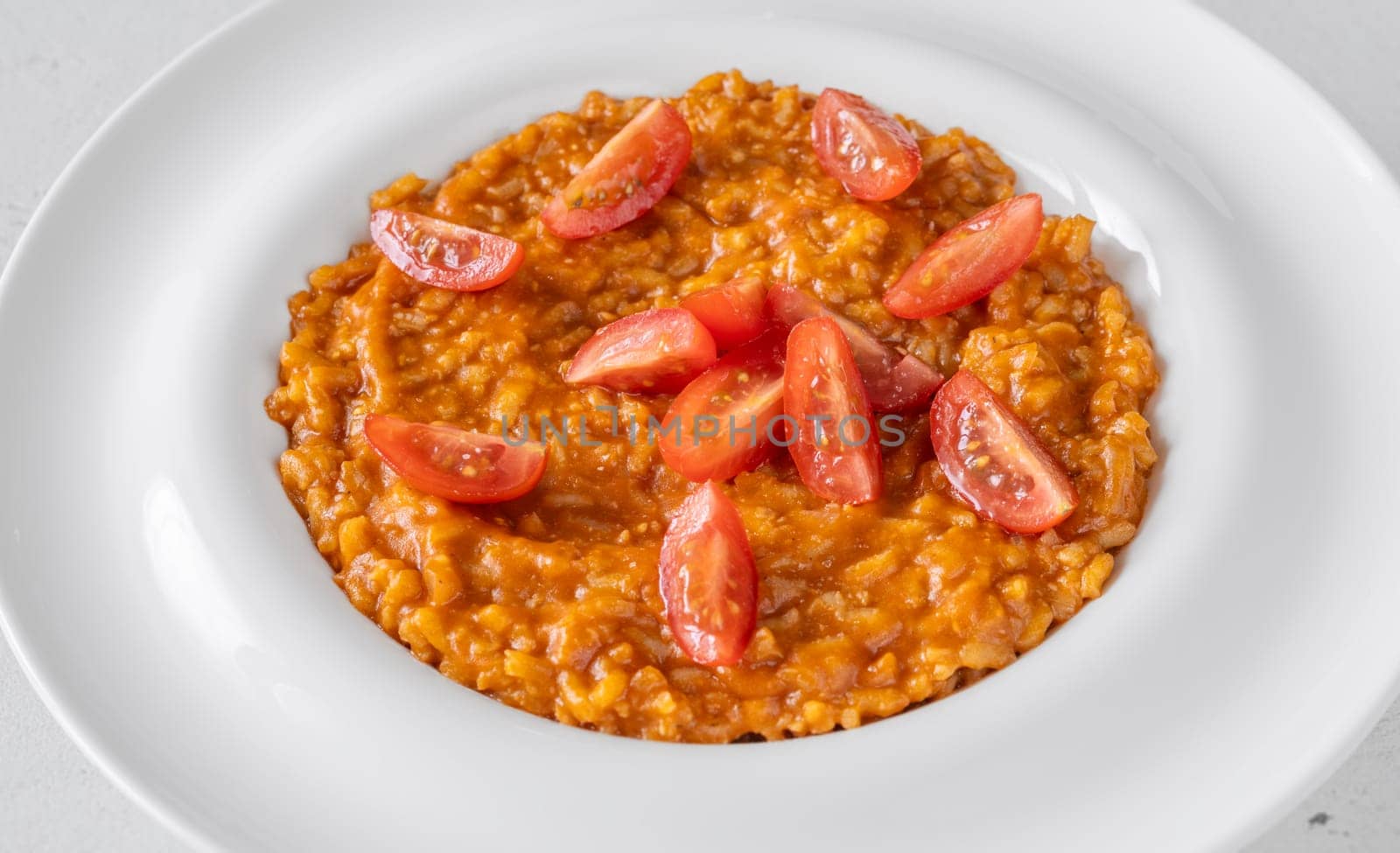 Tomato risotto plated simply with cherry tomato garnish and vibrant warmth
