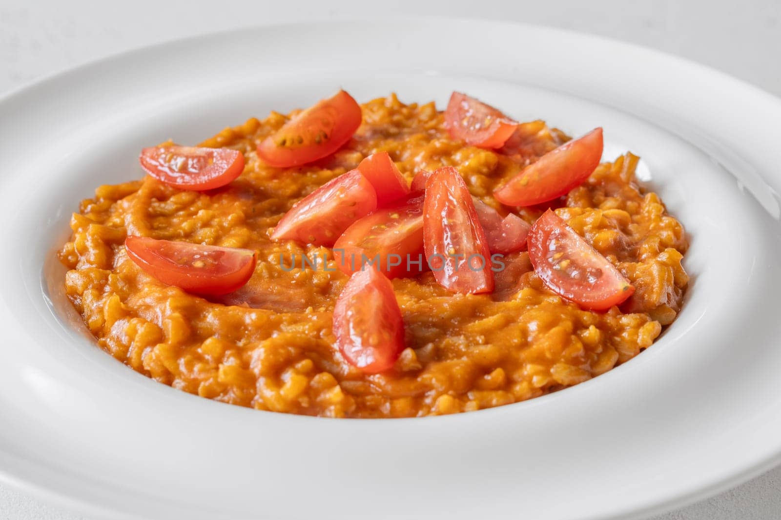 Tomato risotto plated simply with cherry tomato garnish and vibrant warmth