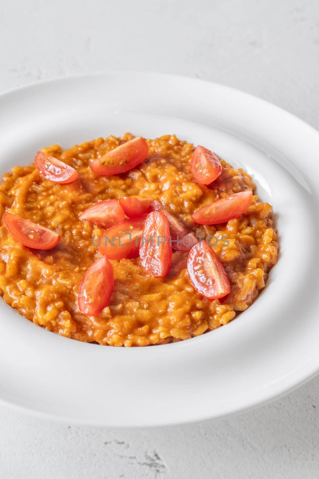 Tomato risotto plated simply with cherry tomato garnish and vibrant warmth