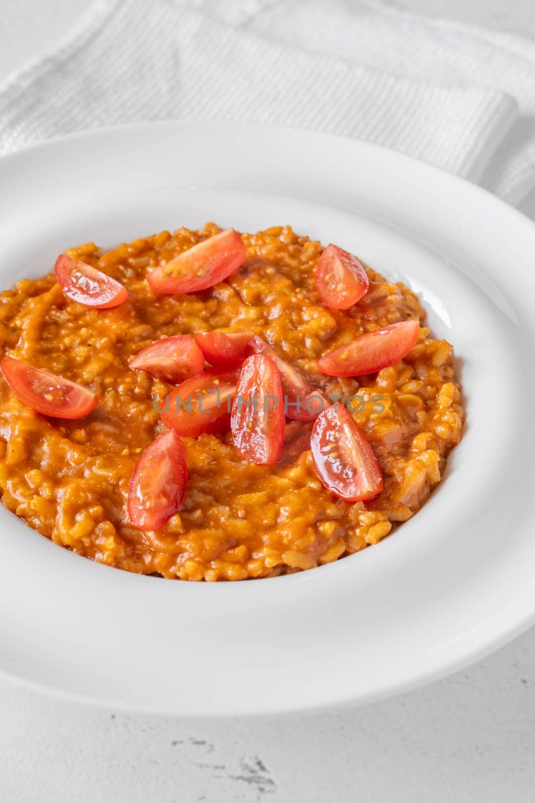 Tomato risotto plated simply with cherry tomato garnish and vibrant warmth