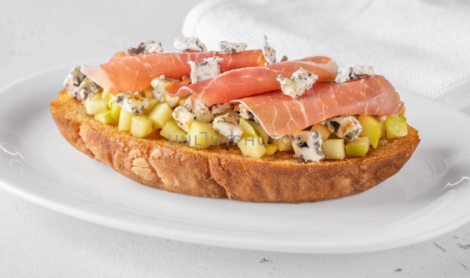 Warm sandwich stacked with creamy cheese, salty ham, sweet apple, and honey
