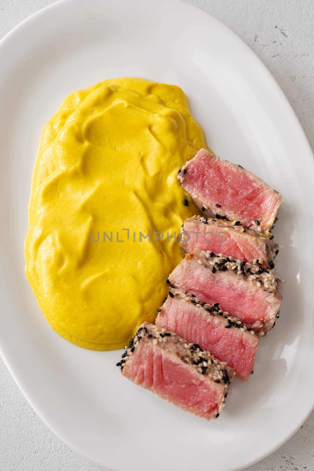 Crisp sesame tuna rests beside smooth cauliflower curry, balanced and visually refined
