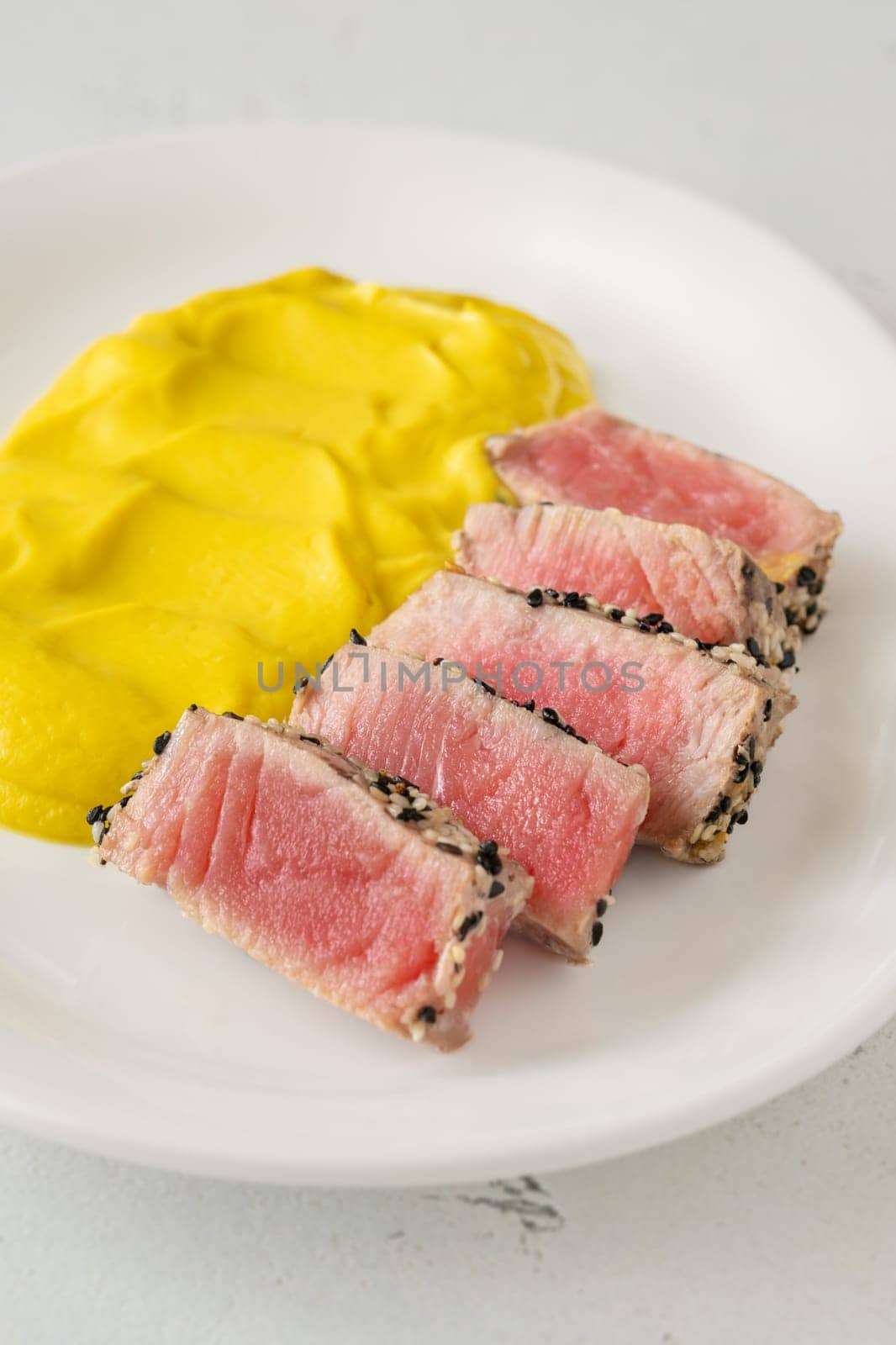Crisp sesame tuna rests beside smooth cauliflower curry, balanced and visually refined
