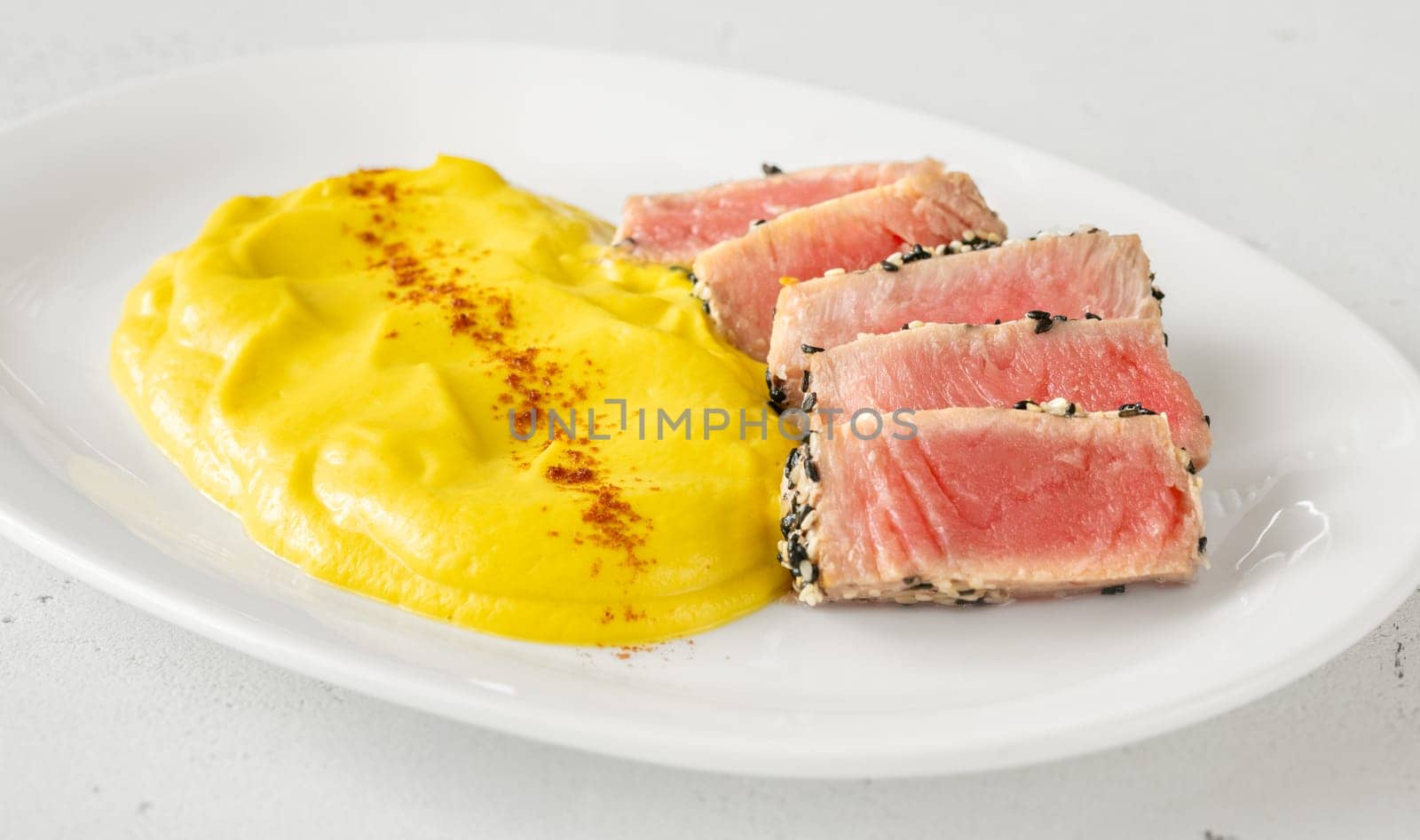 Crisp sesame tuna rests beside smooth cauliflower curry, balanced and visually refined